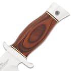 It has a contoured, reddish wood grip with silver accents and a stainless steel pommel and guard