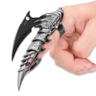 The claw knife is shown on a hand, with focus on the scale-like detailing of the finger cover. 