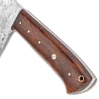 Detailed view of the wooden handle scales of the knife, secured by brass pins with brass lanyard hole at the top.