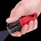 A hand is shown holding the knife, showcasing the LED flashlight on the side.