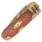 The handle scales are brown wood and have an inset shiny gold decorative metal accent and a bolster with spring accents