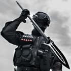 A personal in full black tactical gear is shown wielding the M48 Magnum Spear. 