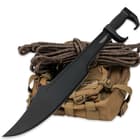 The 23” 1065 high carbon steel blade with black, hard-coated finish is shown leaned against some tactical gear. 