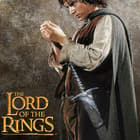 Lord of the Rings Frodo holds gold ring with intense stare with sting sword shows runes engraved on blade and handguard
