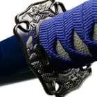 The cast tsuba of each of the three samurai swords features a dragon design beneath the blue cord wrapped handle. 