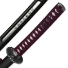 The scabbard has an opening on the side to showcase the Japanese inscription and the handle has plum colored cord wrap. 