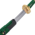 Zoomed view of japanese sword with a steel blade pulled out of black casing with a green nylon cord wrapped around the handle

