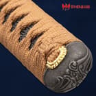 The pommel of the katana is shown with intricate wave-like design atop the brown cord wrapped handle. 
