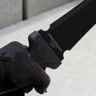 Closeup of a gloved hand holding the Combat Commander gladiator sword with “Combat Commander” on the blade. 