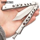 A hand is shown holding the skeletonized stainless steel handles slightly open, showing the stainless steel tanto blade.