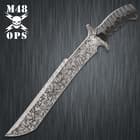 M48 combat machete with titanium electroplated blade finish and matte black TPU handle with textured grooves. 
