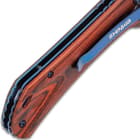 An angled view of the reddish-brown wooden handle scales with metallic blue screws and blue liner.