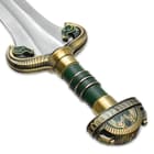 Brass plated pommel with two horse heads leading to green enameled grip and false edge hugging the stainless steel blade

