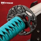 The katana tsuba is intricately designed with two monkey faces just beneath the ray skin handle with teal cord wrapping. 