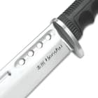 Close view of stainless handguard extended to the carbon steel blade with Honshu etched on the inner facing of the sword
