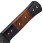 The glossy handle scales are crafted of weathered black wood and rich brown wood, secured with brass pins and a rosette