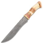 The magnificent knife has a 7 3/4”, keenly sharp Damascus steel blade with a slim, upswept profile and beveled edge