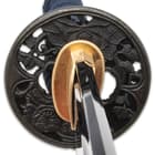 The intricate, dark metal alloy tsuba has a lotus design and the design is carried through to the pommel