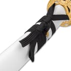 Zoomed view of black cord wrapped around shaft of white lacquered scabbard
