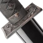 Just above the tsuba, at the bottom of the cord wrapped handle, is an antiqued brass collar with themed design. 