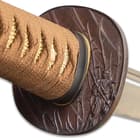 The hardwood handle is wrapped in genuine, tea-colored rayskin and brown cord and features brass dragon menuki