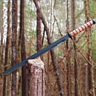 The sword’s 19 3/4” black-coated blade is shown sliced into a tree trunk.