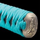 The teal braided cord of the handle wraps through the ornate pommel featuring a bearded man. 