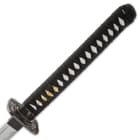 The hardwood handle is traditionally wrapped in faux rayskin and black cord and has an intricately detailed metal tsuba