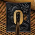 Tsuba with black dragon aside full view of the katana with black Damascus blade and black lacquered scabbard with view of detailing on pommel. 