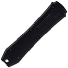 Closed small non-reflective black automatic OTF knife with small hole at the bottom center and sliding trigger button. 
