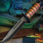 7" black finished steel blade fighter knife with a stacked leather handle on a background of green utility gear.
