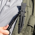 Black "Undercover" stinger knife being held through the open ring pommel in front of black knife sheath attached to utility jacket. 
