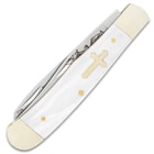 The faux pearl handle scales have an inlaid brass cross