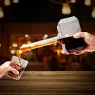 This image shows a glass decanter in the shape of thor's hammer being used to pour a drink.
