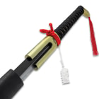 The wooden handle is wrapped in white, faux rayskin and black cord and it features a gold metal handle with a red tassel