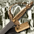 Zoomed view of the brass handle of the Battle of Bunker Hill sword shown in front of a historic war photo. 