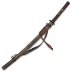 The 39” katana slides into a distressed leather-wrapped wooden scabbard, which has an adjustable leather shoulder strap