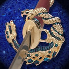 Zoomed view of the gold and blue dragon and serpent design of the tsuba, just beneath the simulated snake skin handle. 
