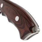 The finger-grooved, brown pakkawood handle scales are attached to the full-tang with large stainless steel pins