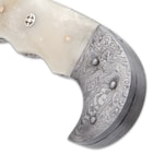 The curved Damascus steel handle has cream-colored bone handle scales, accented with mosaic rosettes and brass pins
