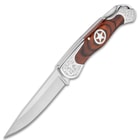 Shown open, the knife has a 3 1/2" 3Cr13 stainless steel blade with wooden handle and silver star medallion.