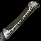 Upclose view of a dune replica knife with intricate glyphs and patterns along the handle with some artificial aging. 
