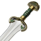 Zoomed view of solid metal guard and pommel with green accents and false edge guard with two horse heads
