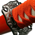 Detailed view of the cast tsuba with dragon design just beneath the red cord wrapped handle. 