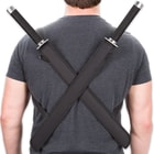 The twin swords strap across each shoulder in their respective black sheaths. 