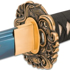 It has a 27” 1045 carbon steel blade with a dark blue finish, which extends from an antique gold-toned ocean-themed tsuba