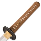 Magnified view of samurai sword handle with genuine rayskin wrapped with brown japanese cord attached to iron handguard
