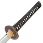Zoomed view of the white ray skin handle with black braided cord wrapped and brass menuki. 