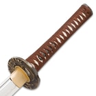Detailed view of the white genuine ray skin handle wrapped in brown cord with menuki. 