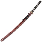 The 40 9/10” overall katana slides smoothly into its red lacquered wooden scabbard, accented with black splashes